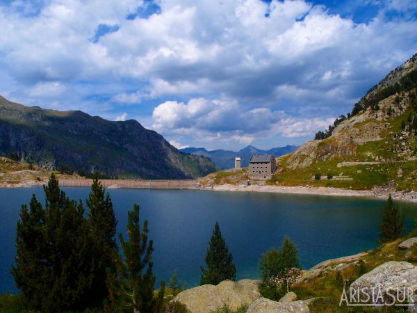 Al fondo la presa, que cruzaremos de izquierda a derecha, pasaremos por el refugio y seguiremos bordeando el lago hasta donde se ha realizado la foto